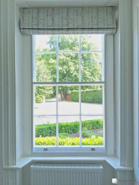 Light green timber sash window fitted with two part split-panel WindowSkins magnetic secondary glazing using the Subframe placement