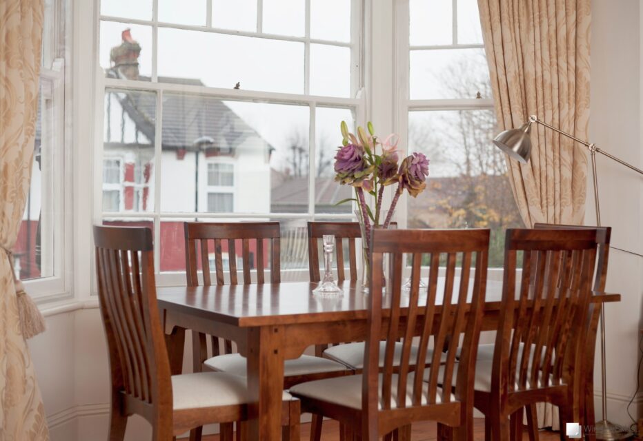 Dining table with three sash window, fitted with WindowSkins secondary glazing, visible in the background