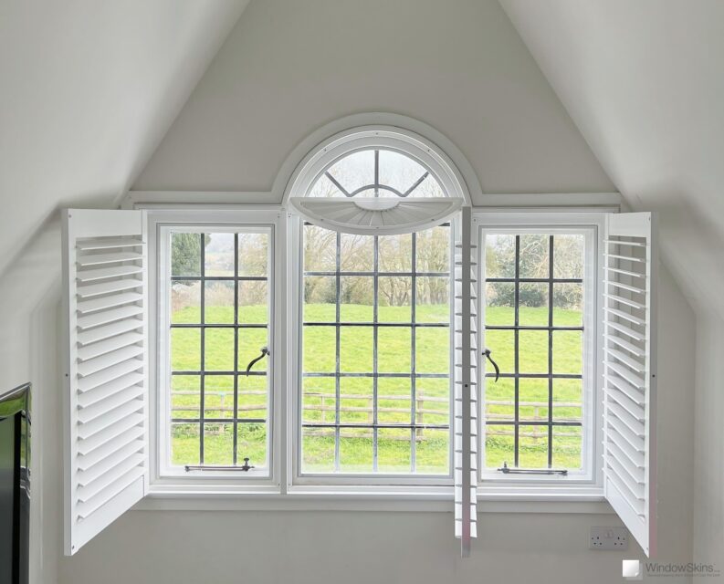 Timber, steel and leaded casement windows fitted with arched magnetic secondary double glazing and arched plantation shutters