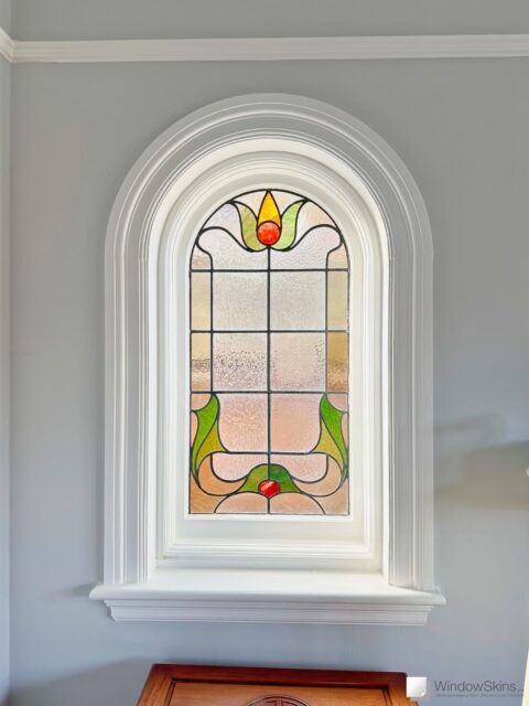 Arched stained glass casement window fitted with WindowSkins magnetic secondary glazing