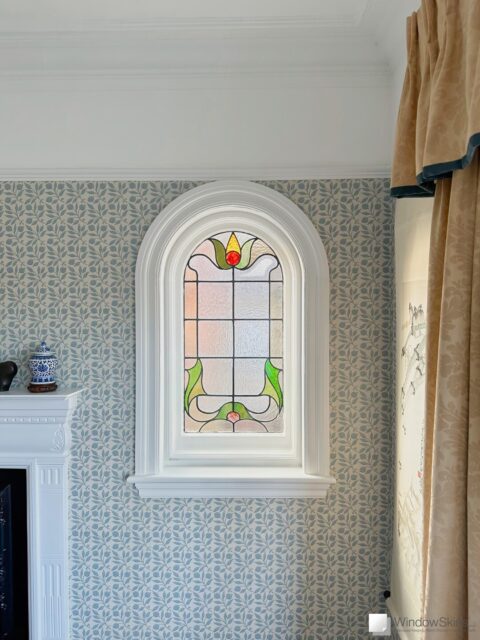 Small arched stained glass casement window fitted with WindowSkins magnetic secondary glazing