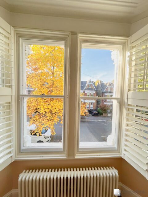 WindowSkins magnetic secondary glazing, with split panel and subframe, fitted to a pair of white sash windows with white plantation shutters
