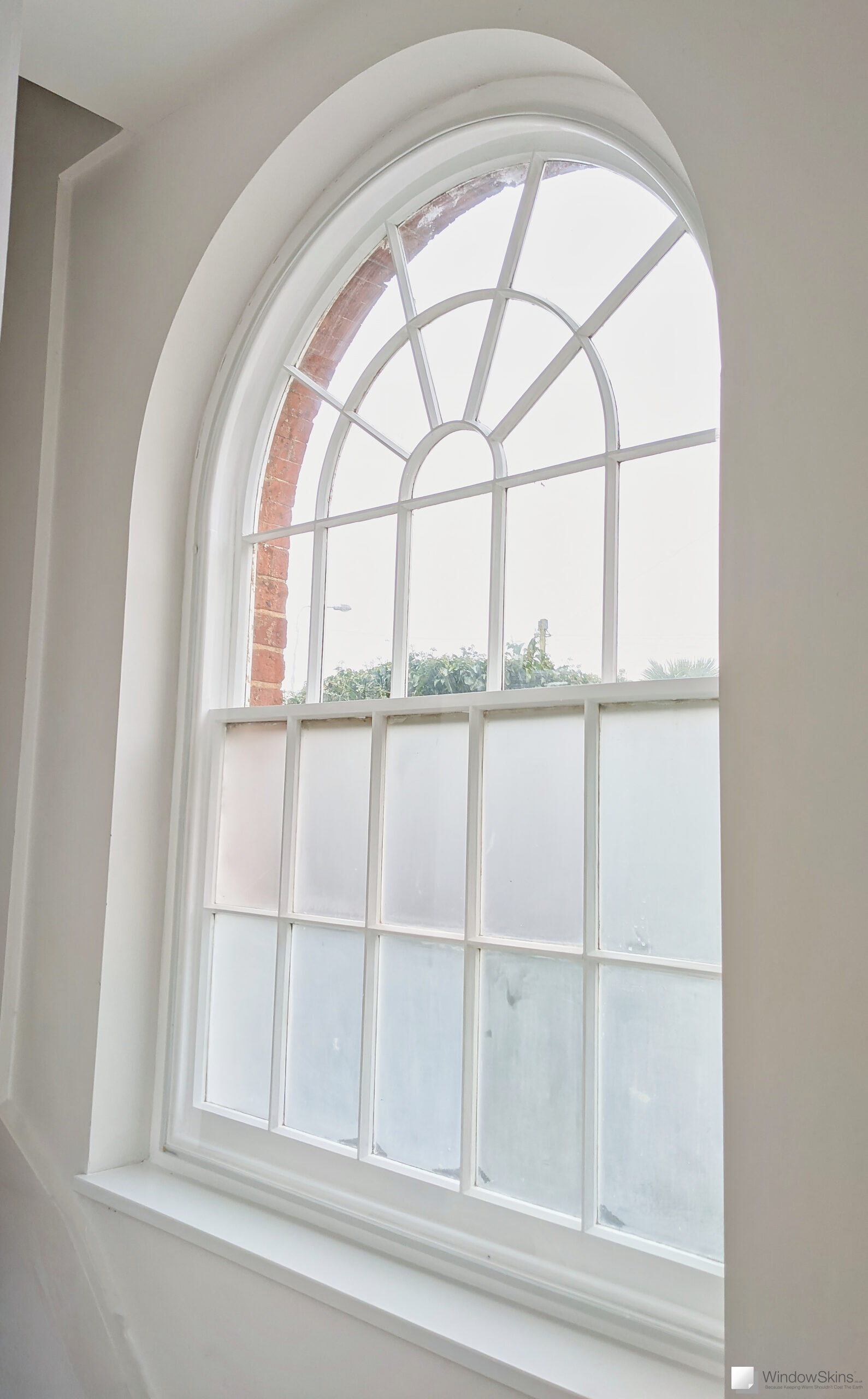 Magnetic secondary glazing fitted in the outer placement to a white arched sash window