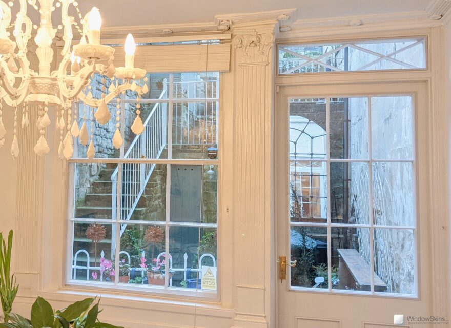 Basement front door and adjoining sash window fitted with secondary glazing to reduce cold and draught
