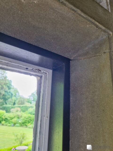 Top right closeup of a painted timber frame fitted to a stone mullion window in a listed property
