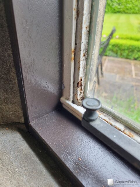 Bottom left closeup of a painted timber frame fitted to a stone mullion window in a listed property