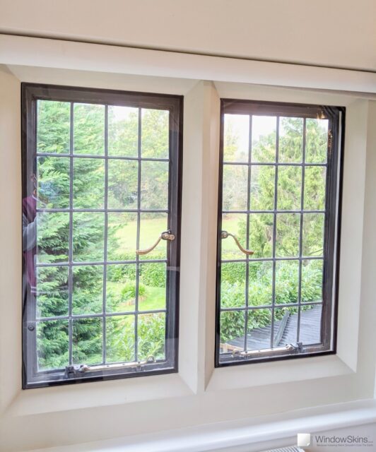 Pair of metal windows with leaded lights set in stone mullion and fitted with secondary double glazing using a bespoke subframe