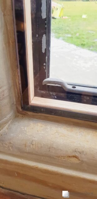 Closeup of an oak subframe fitted with dark brown magnetic secondary glazing panel within a stone mullion