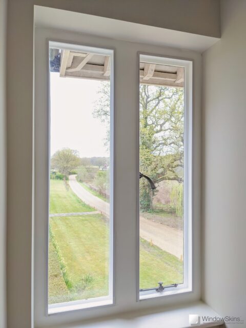Pair of white painted stone mullion windows at a listed property fitted with WindowSkins secondary glazing