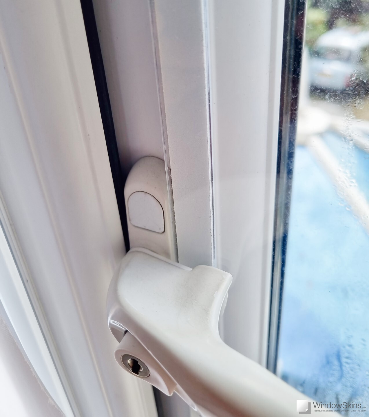 Close-up of a magnetic triple glazing panel retrofit to a double glazed uPVC window. The window handle can be seen in the open position, demonstrating adequate space for the glazing panel to fit underneath without causing an obstruction
