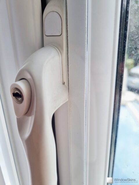 Close-up of a magnetic triple glazing panel retrofit to a double glazed uPVC window. The window handle can be seen in the closed position, demonstrating adequate space for the glazing panel to fit alongside without causing an obstruction