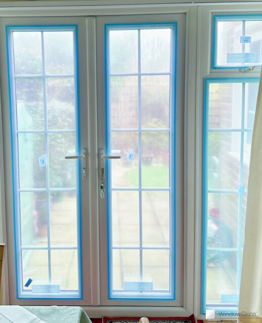 Magnetic triple glazing being installed on double glazed French uPVC patio doors to improve insulation and reduce heat loss. Note the blue protective film